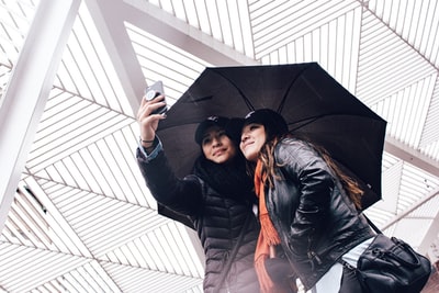 Two women take while with an umbrella
